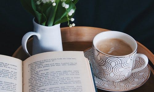 Åpen bok på et bord med en kaffekopp